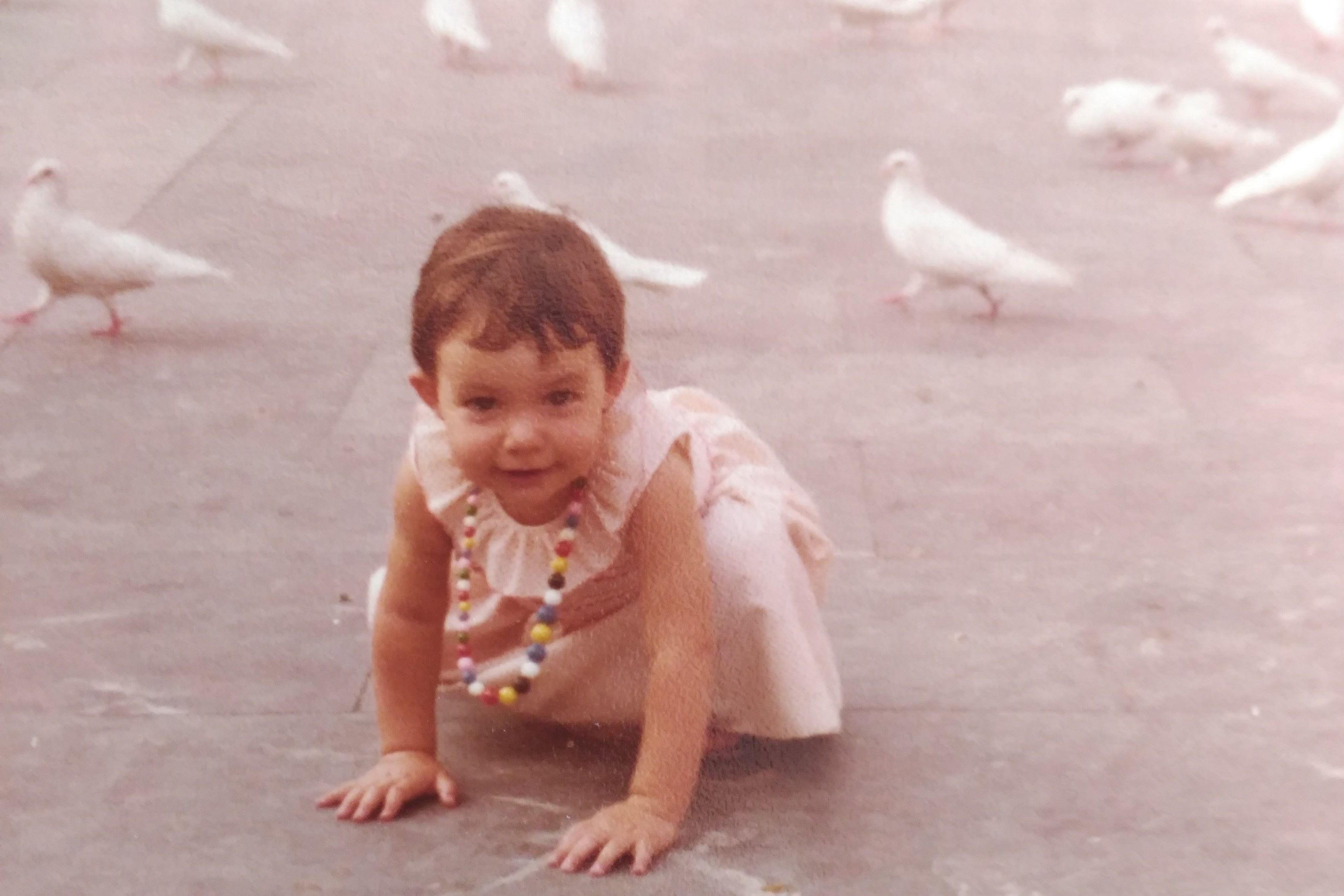 Niña jugando entre las palomas