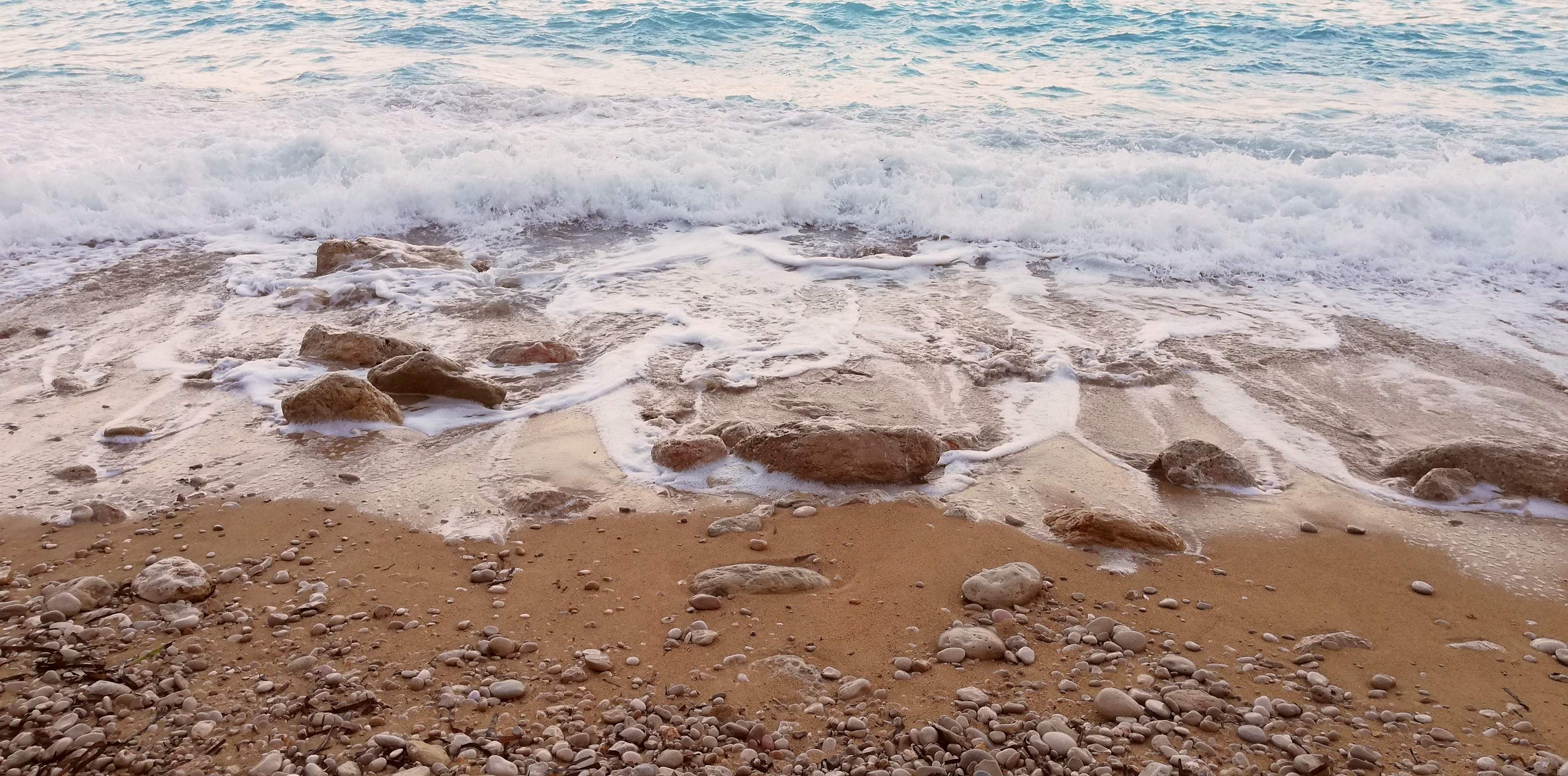 Olas bañando la arena y las rocas